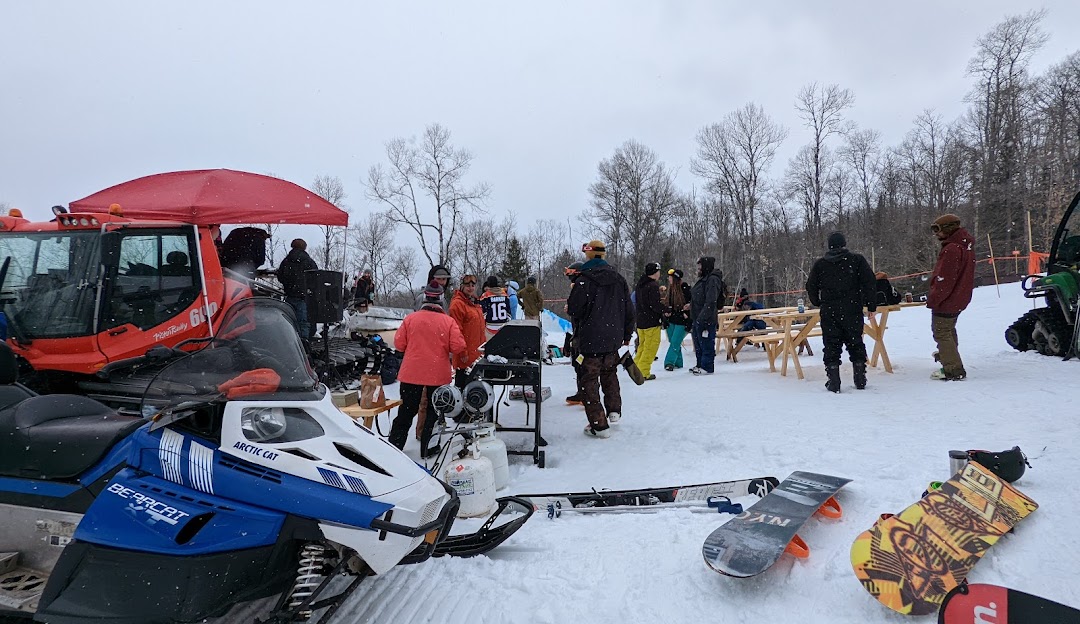 Winter sports scene at Searchmont, Ontario with a snowmobile parked nearby a chalet amidst stunning snowy scenery, at a ski resort.