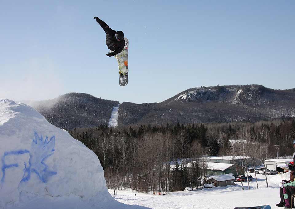 A snowboarder carving through the pristine snow at Searchmont, Ontario, showcasing the exhilarating winter sports opportunities in Canada.
