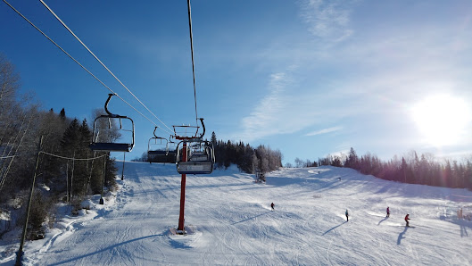 Ski lift and chalet at Searchmont ski resort in Ontario, Canada during a bustling winter sports scene, with a skier dazzling down the snow-covered mountains.