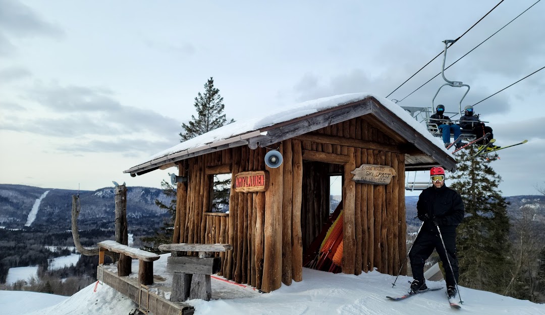 A winter sports scene at Searchmont ski resort in Ontario Canada featuring a ski lift a mountain hut and a sports centre amidst a snow-covered landscape.