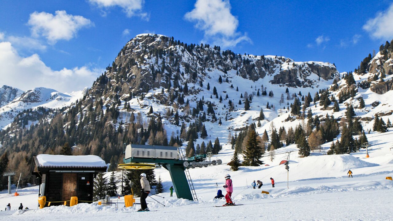 Passo San Pellegrino | ​Falcade in Italy - a group of people skiing down a snowy slope.