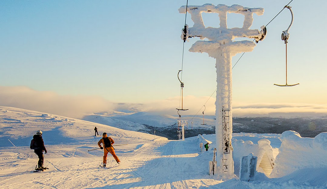 Winter sports enthusiasts enjoy a day at Bydalsfjällen, a ski resort in Northern Sweden, featuring a ski lift and skiers against a picturesque snow-blanketed landscape.