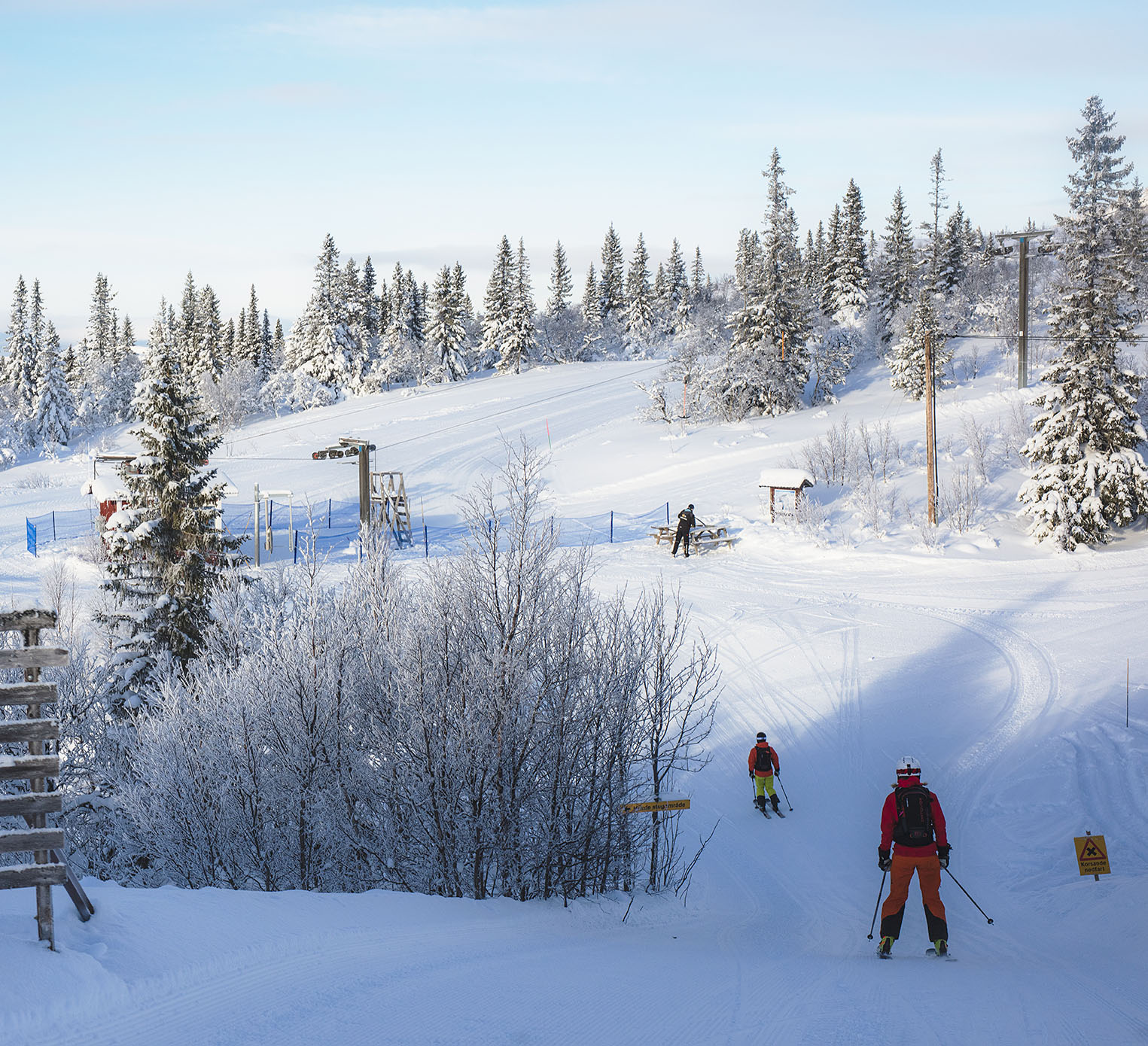 A vibrant winter sports scene at Bydalen Northern Sweden featuring a ski resort filled with families enjoying skiing against a stunning backdrop of snowy slopes and mountains.
