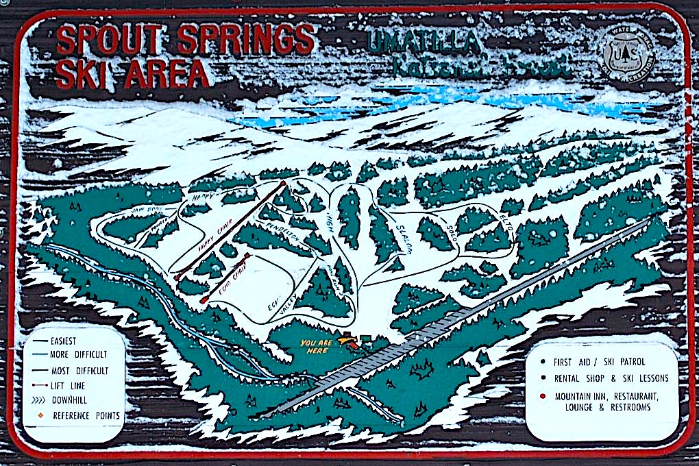 Winter scene at Spout Springs in Weston, Oregon, highlighting a bustling ski resort with snow-covered slopes, filled with winter sports enthusiasts. Visible in the scene is a ski lift transporting skiers uphill.