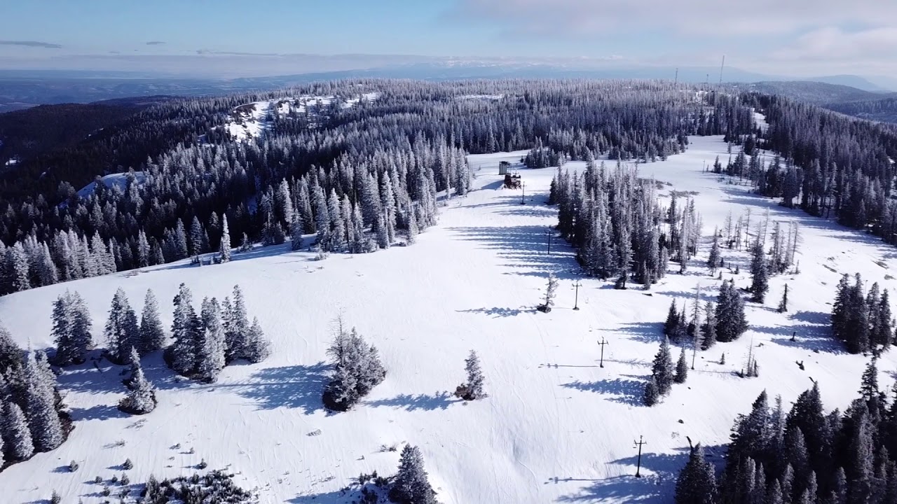 View of Spout Springs ski resort in Weston, Oregon, showcasing a winter sports scene. Skiers and snow-covered slopes are visible, with a ski lift seen operating in the backdrop.