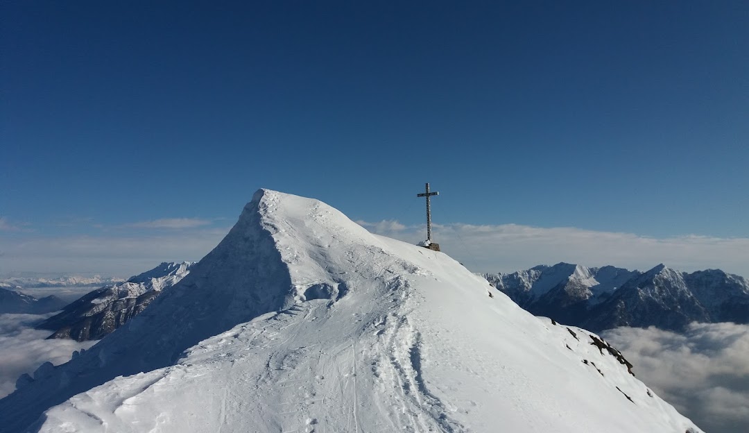 A scenic view at Domobianca in Piedmont, Italy featuring a picturesque chalet nestled against a snowy mountain, with a skier enjoying the winter sports scene.