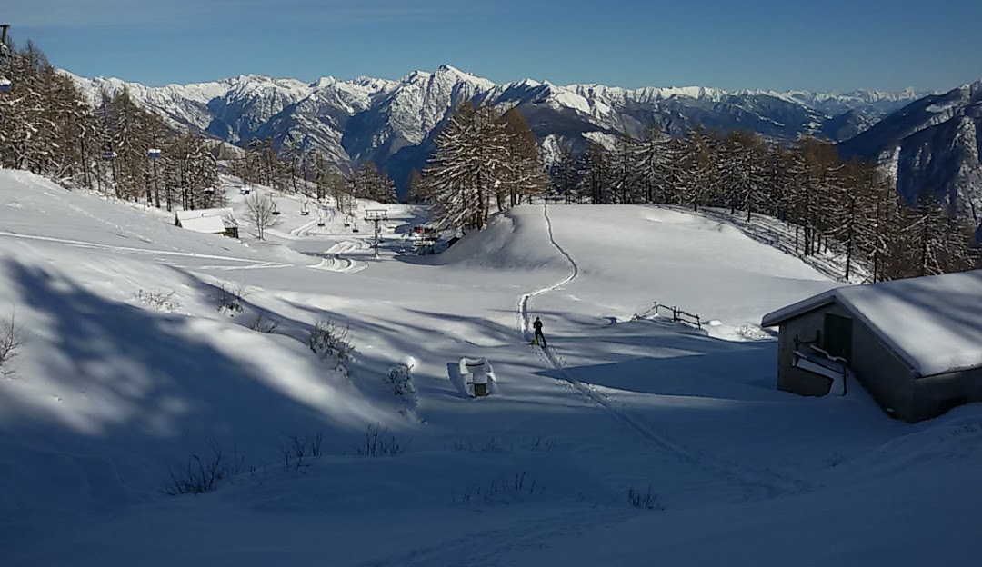 Winter sports enthusiasts enjoy a day at Domobianca ski resort in Piedmont, Italy surrounded by beautiful winter scenery and a charming chalet.