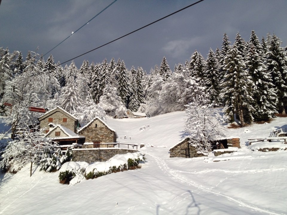 Image of the charming Domobianca in Piedmont, Italy showcasing a cozy chalet amidst a picturesque winter scene. A winter sports centre is faintly visible, hinting at the bustling winter activities.