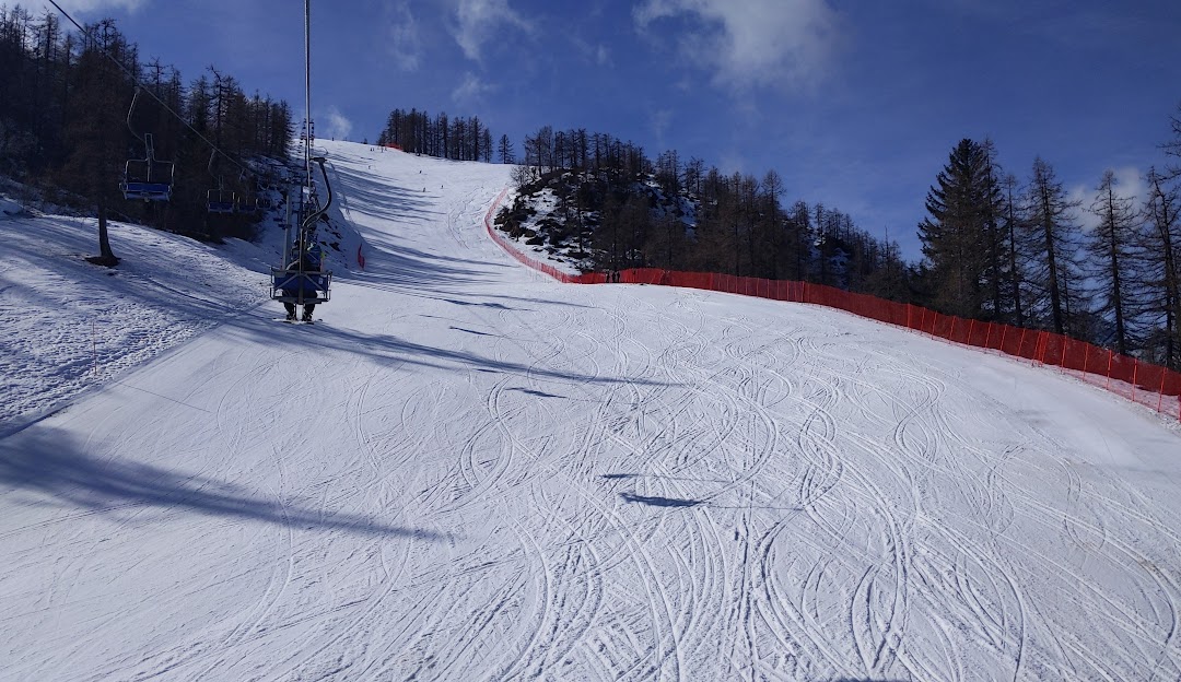A skier is descending a slope at the Domobianca ski resort in Piedmont Italy with a charming chalet in the backdrop creating a picturesque winter sports scene.