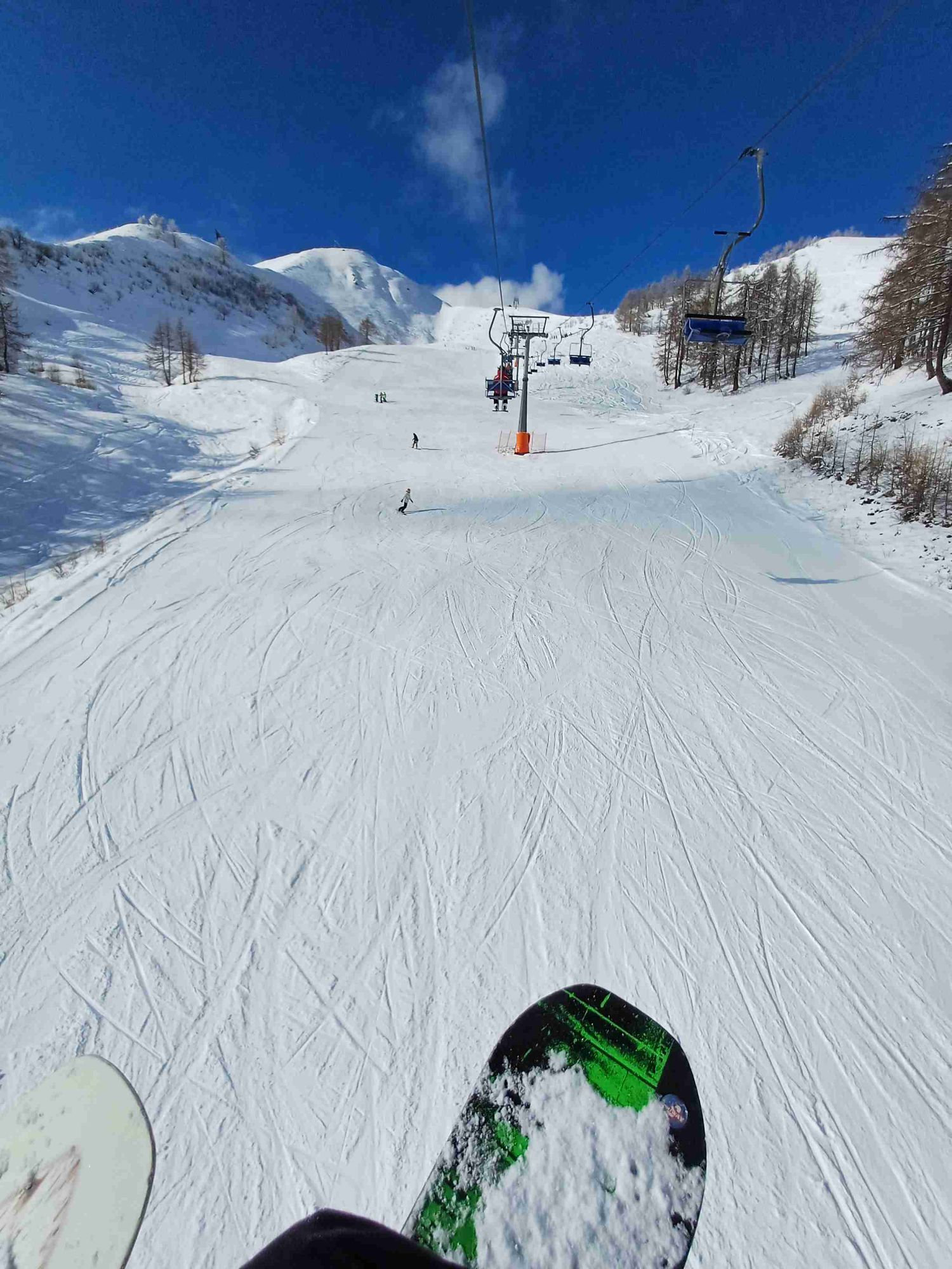 A skier enjoys the snowy slopes at Domobianca ski resort in Piedmont, Italy. A charming chalet sits in the background, with a ski lift nearby, completing the vibrant winter sports scene.