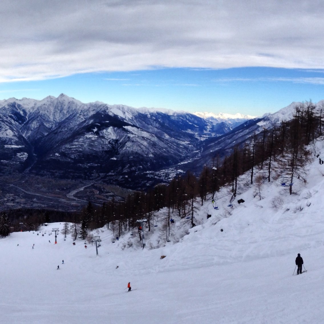 A winter scene at Domobianca ski resort in Italy, featuring a charming chalet nestled in the snow-covered slopes, and stunning mountains in the backdrop.