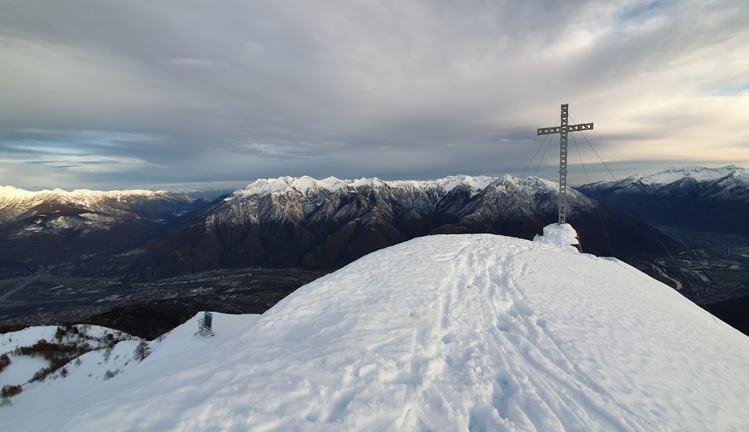 Winter scene at Domobianca in Italy, featuring a snow-covered chalet, towering mountain in the background, and a skier braving the slopes amidst stunning winter scenery.
