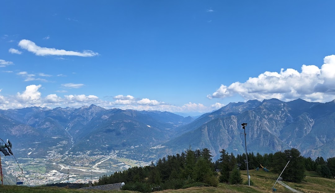 A picturesque view of Domobianca Italy with a charming chalet and ski lift nestled on a sunlit mountainside part of a scenic ski resort.