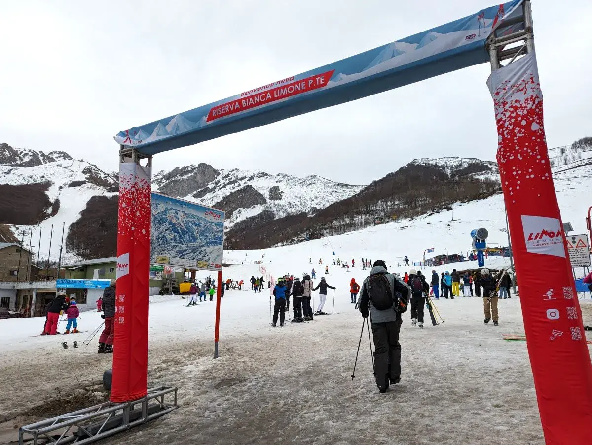 Domobianca in Italy - a group of people skiing down a snow covered slope.
