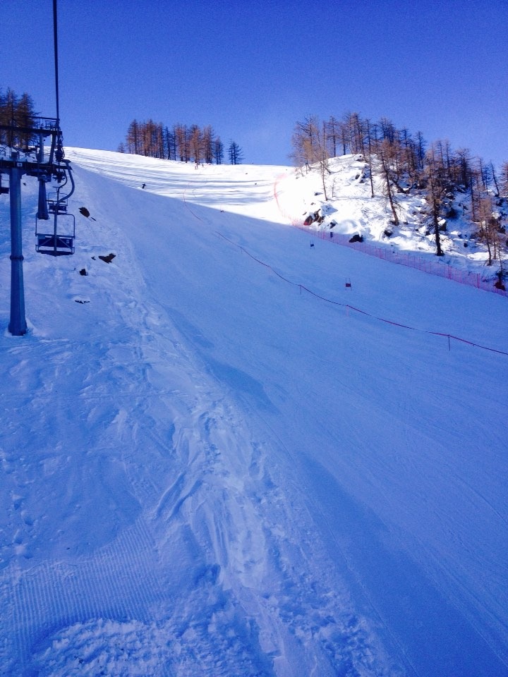 A winter sports scene set within Domobianca ski resort Italy. A skier glides by a cozy chalet with a ski lift operating nearby in the snow-laden landscape of Piedmont Italy.