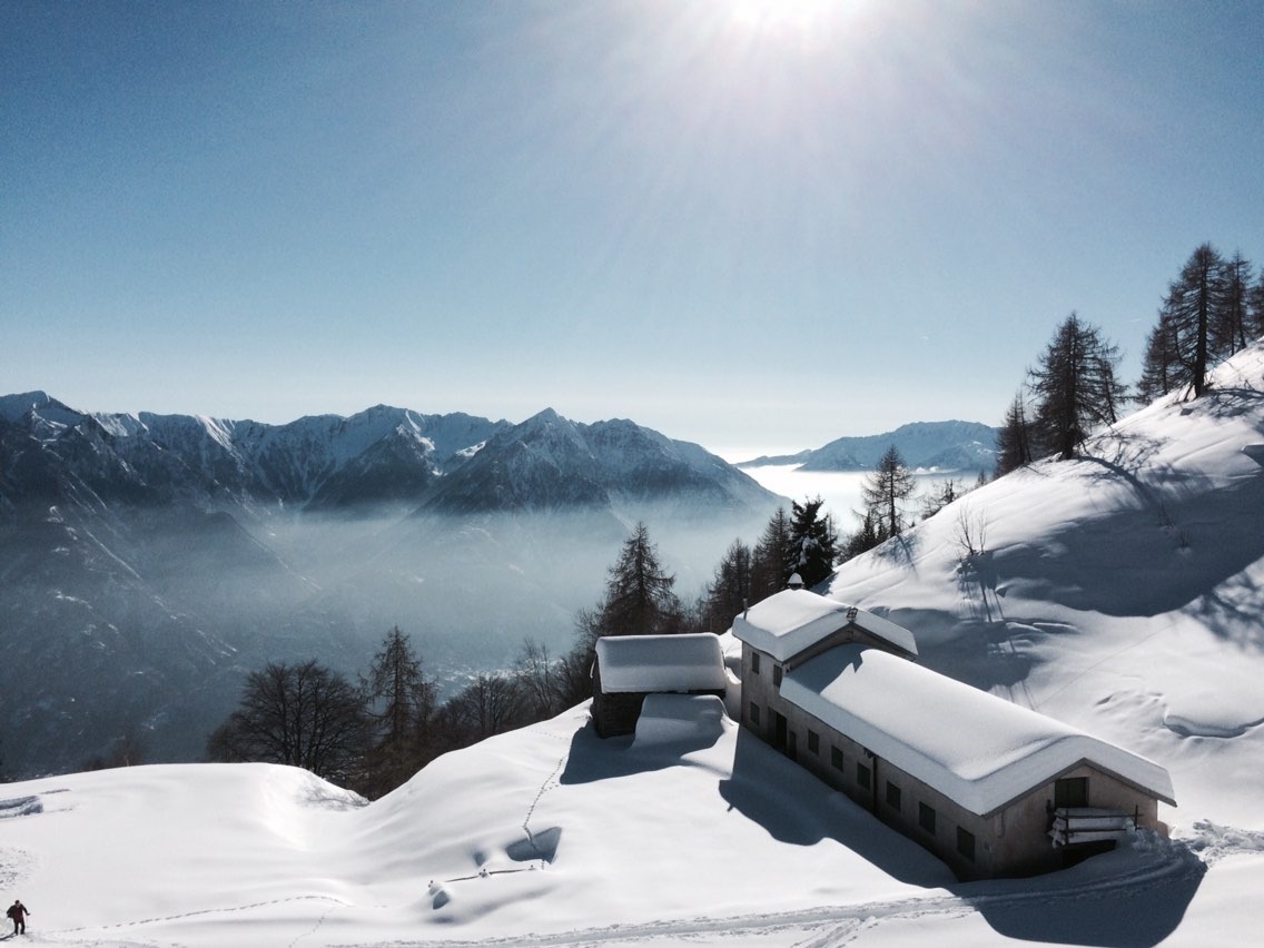 Sunny winter day at Domobianca in Piedmont, Italy with a scenic view of a winter sports scene. Charming chalet amidst the pristine winter landscape clearly contributes to the stunning beauty of the place.
