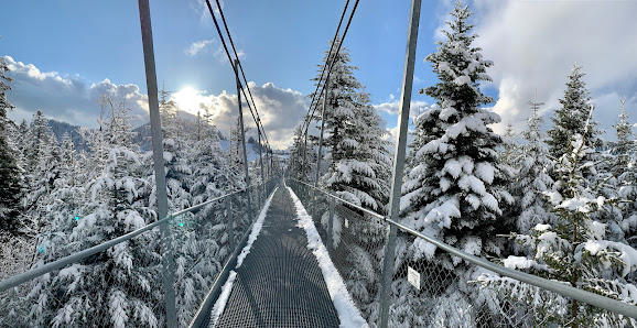 Winter scene in Sattel-Hochstuckli, Switzerland showcasing a serene snow-covered landscape, a ski lift traversing over, a charming challet nestled in and winter sports enthusiasts enjoying the day.