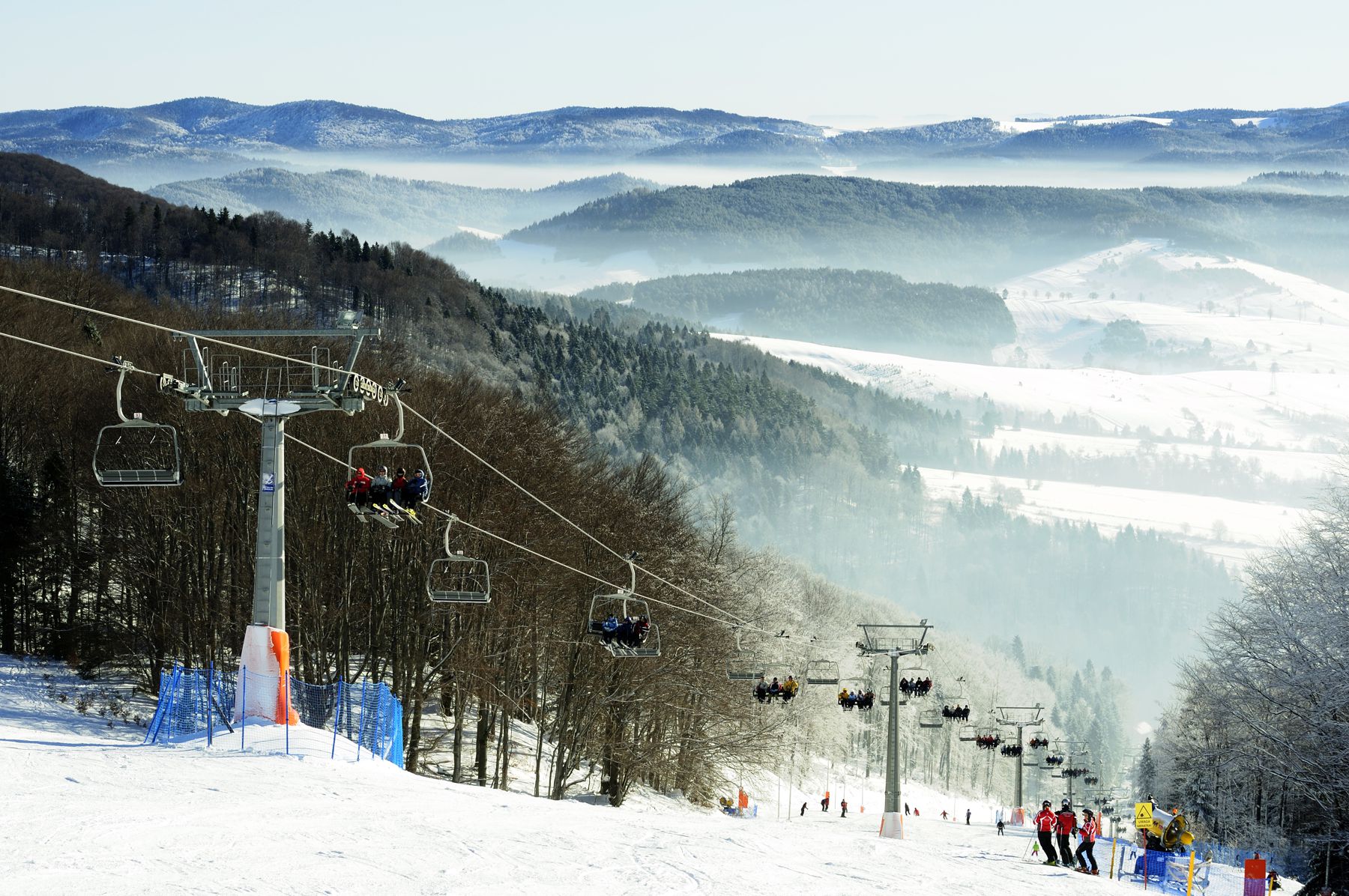 Winter scene at the Dwie Doliny ski resort in Lesser Poland featuring a ski lift against a backdrop of snow-covered hills and pristine natural beauty.