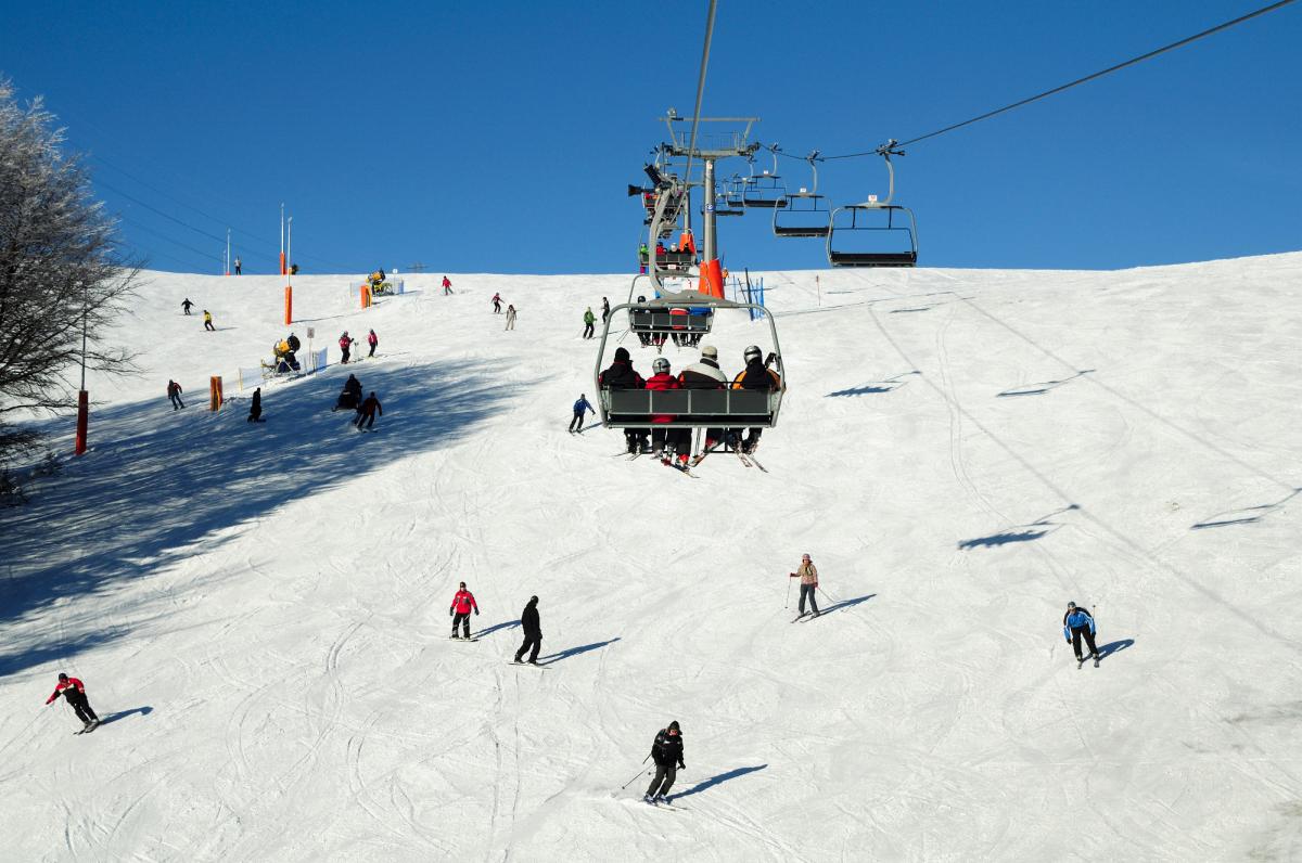 Ski lift at Dwie Doliny - wyciąg krzesełkowy Szczawnik I in Wierchomla Mała, a bustling polish winter sports scene in the heart of a ski resort, with glimpses of a challet and sports centre.