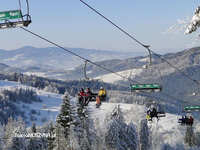 Winter sports scene at Dwie Doliny - wyciąg krzesełkowy Szczawnik I in Poland featuring a ski resort with a ski lift and a group of people skiing amidst stunning winter scenery.