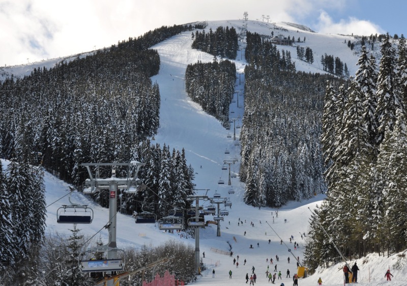 Bansko ski resort in Bulgaria boasts beautiful snow-covered slopes. Winter sports enthusiasts enjoy skiing on the pristine trails, with a ski lift providing easy access to the top. A stunning winter scenery completes the picture.