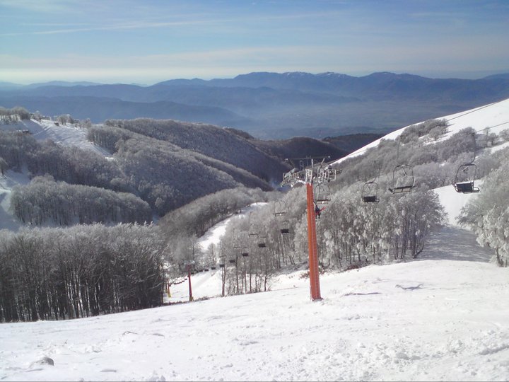 Winter sports enthusiasts enjoying a day at Monte Terminillo ski resort in Rieti, Pian de' Valli, Lazio, Italy, featuring a skier, ski lift, and the stunning mountain backdrop.