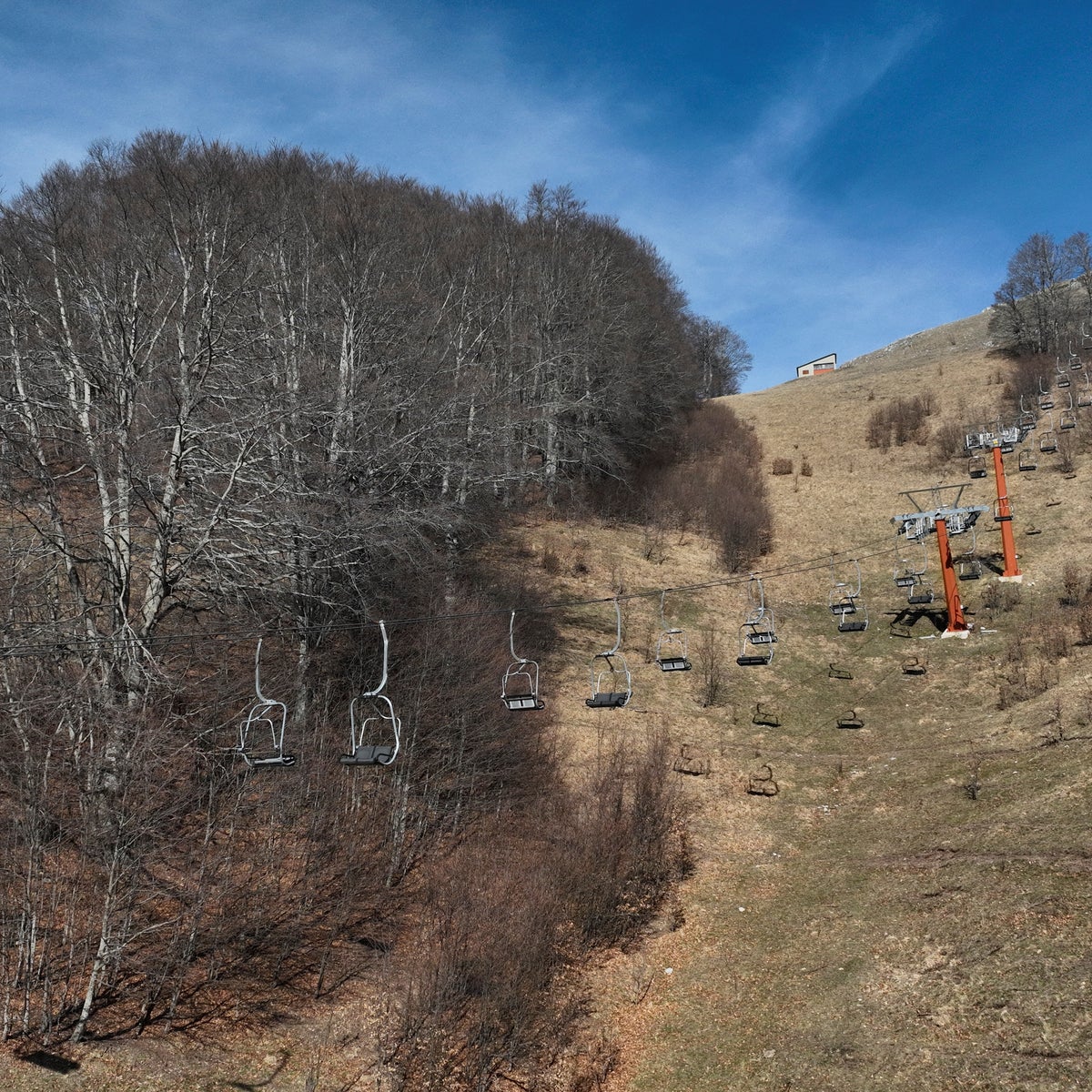 Monte Terminillo in Italy - a ski lift going up a hill on a sunny day.