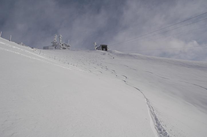 A picturesque view of Monte Terminillo in Italy featuring a charming chalet a skier gliding down the snow-covered slopes and a ski lift nearby. Majestic mountains provide a breathtaking backdrop.
