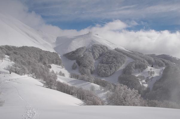 View of a charming chalet nestled amidst a stunning winter scenery at Monte Terminillo in Italy, featuring snow-covered slopes favored for winter sports.