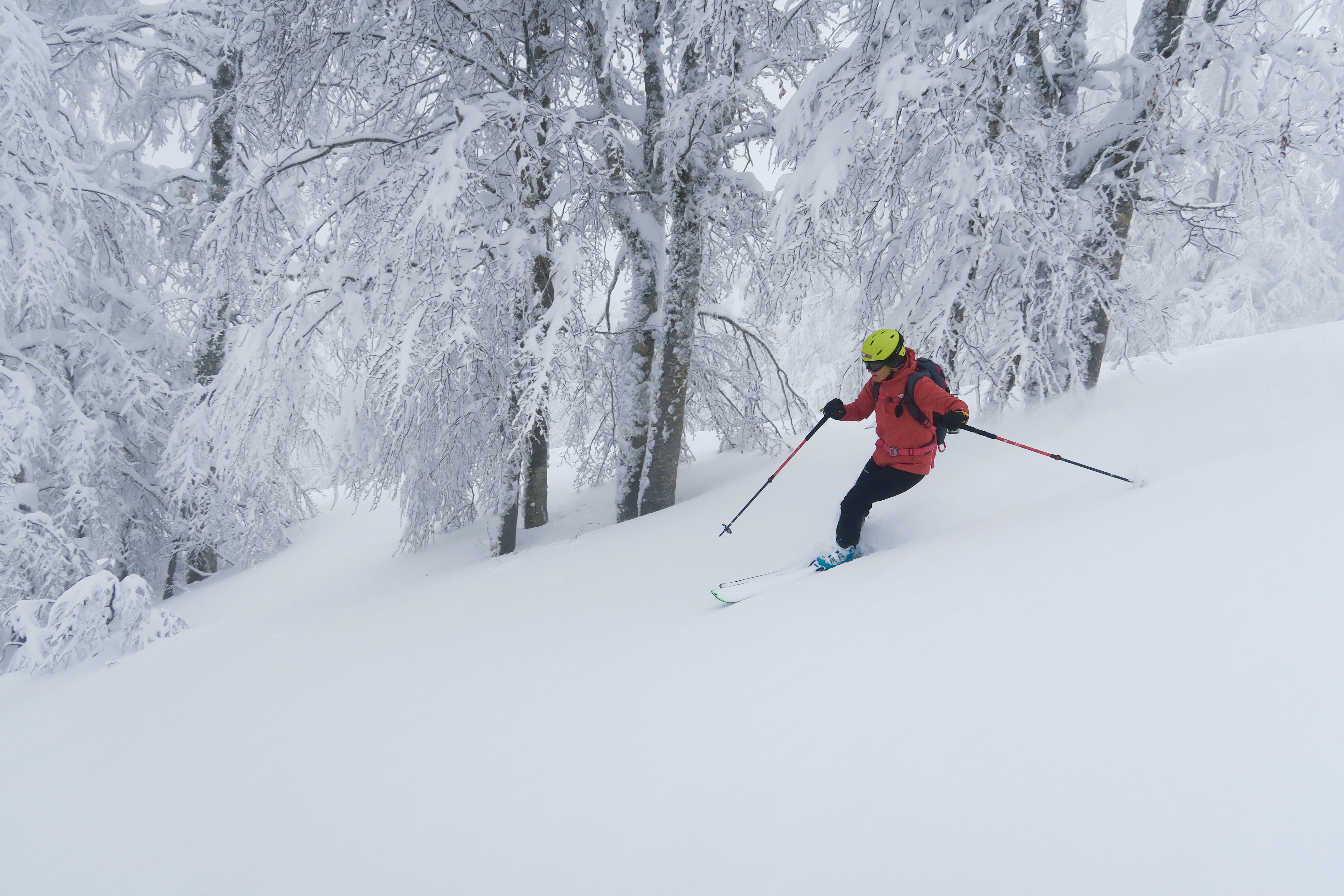A skier descending a mountain at Monte Terminillo in Rieti, surrounded by a winter sports scene with a distant chalet in sight.