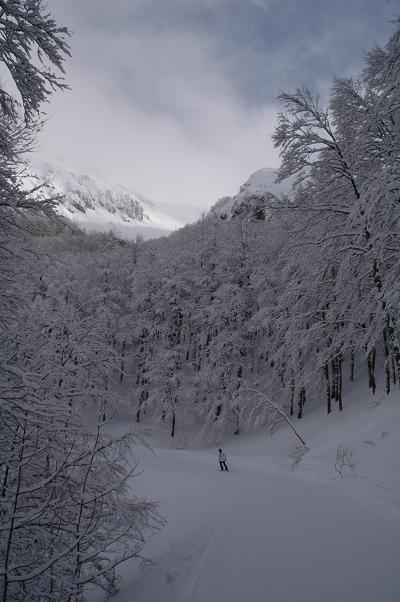 Winter scene at Monte Terminillo in Rieti, Pian de' Valli, Lazio, Italy, featuring a chalet nestled amidst snow-covered terrain, skiers enjoying winter sports, and majestic white mountains.