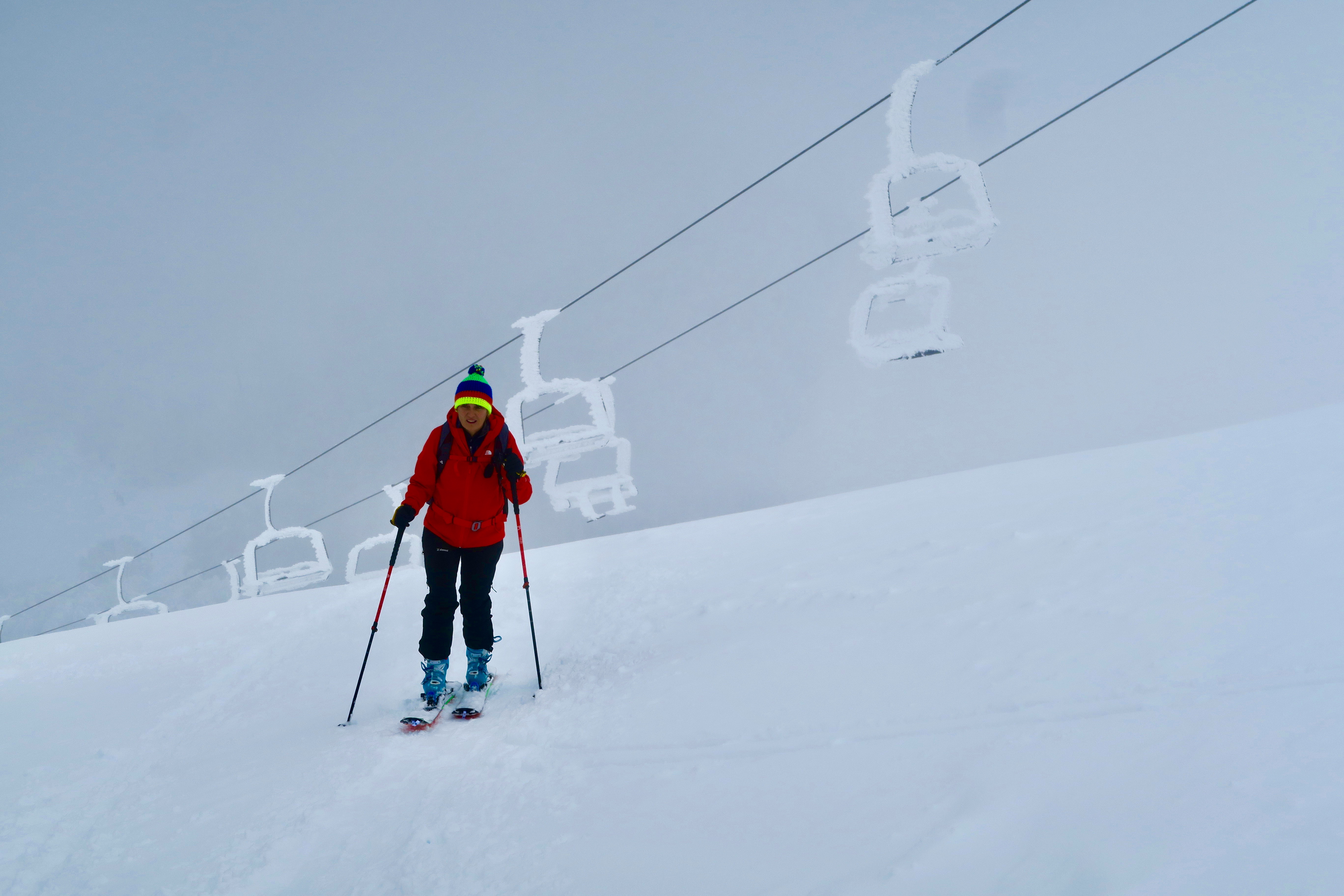 A skier gliding down the snowy slopes of Monte Terminillo in Italy, with a ski lift and chalet in the background, presenting a typical winter sports scene.