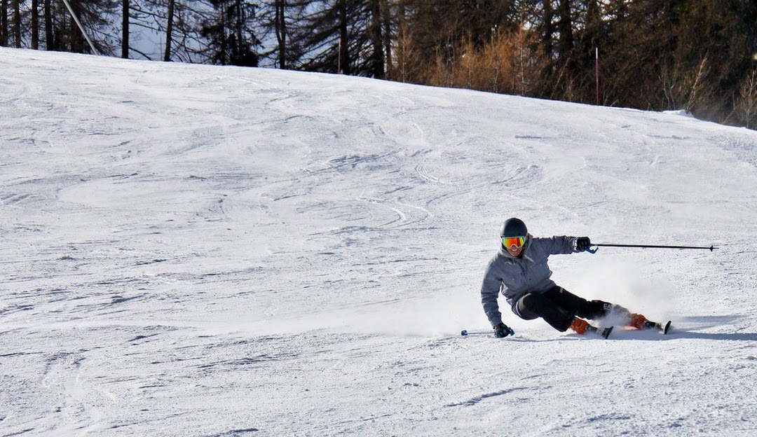 A skier enjoying a run down the snowy slopes at Marquette Mountain in Michigan, USA, with a hint of a ski resort and a chalet visible in the background.