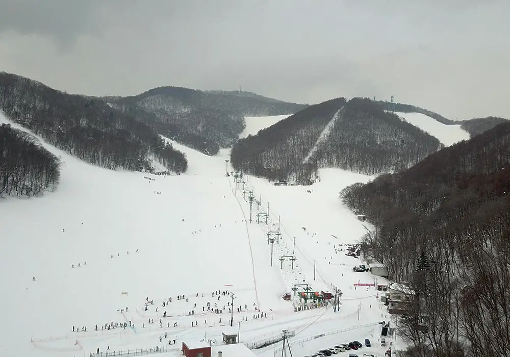 View of Moiwayama Ski Jominamishamen in Kitanosawa, featuring a bustling winter sports scene on the snow-covered slopes amidst stunning winter scenery.