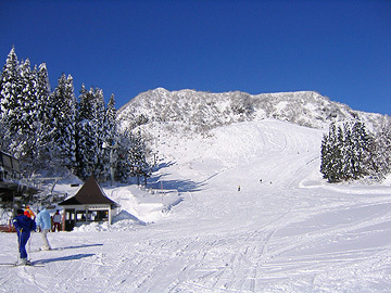 View of Chateau Shiozawa in Japan featuring a ski resort with snow-covered slopes, a visible ski lift, and scenes of winter sports activities.