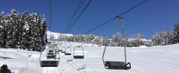 View of Chateau Shiozawa in Japan, featuring a ski lift ascending a snow-covered slope. The breathtaking winter scenery embodies an active ski resort atmosphere.