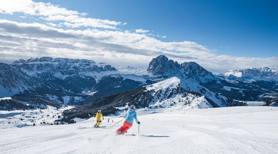 Val Gardena in Italy - two skiers skiing down the slopes of a mountain.