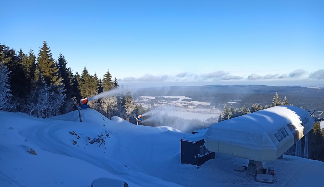 A ski resort in Ož - Orlické Záhoří, Czech Republic during winter, featuring a bustling winter sports scene with a ski lift against the backdrop of stunning winter scenery.