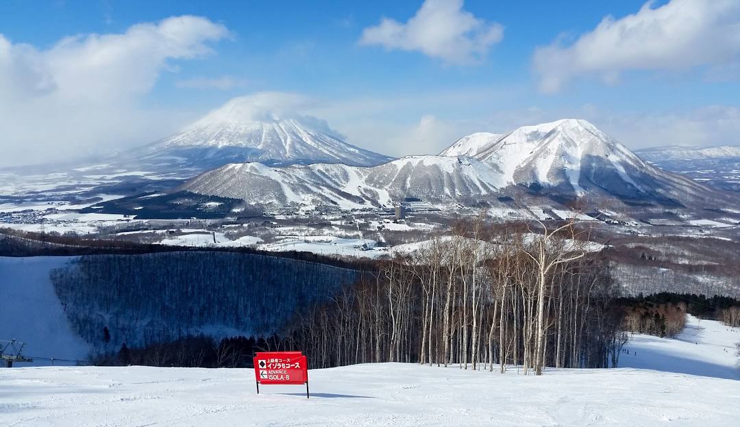 A scenic view from West Mountain in The Adirondacks, Queensbury, New York, showcasing a bustling ski resort with skiers enjoying various winter sports, amidst a stunning winter landscape featuring a ski lift and expansive mountain terrain.
