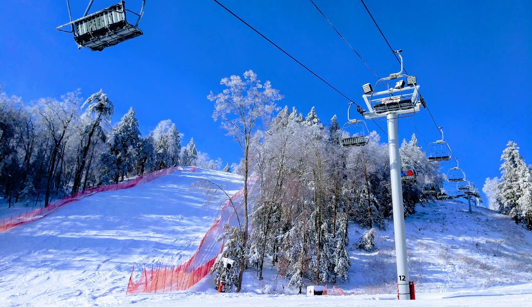 Winter scene at West Mountain ski resort in The Adirondacks, Queensbury, New York, featuring a ski lift ascending the snowy mountain, skiers enjoying winter sports, and a charming challet.