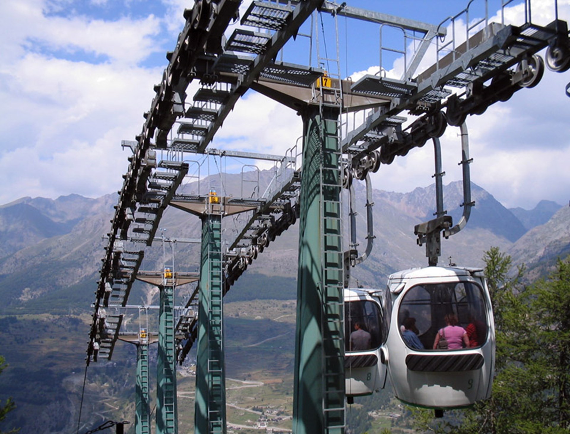A ski lift traverses the snowy landscape of the Cogne – Gran Paradiso in Italy, drawing attention to the distant ski resort and charming chalet nestled amongst the mountains.