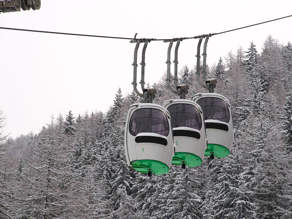A picturesque view of the Cogne – Gran Paradiso ski resort in Italy, featuring a ski lift moving through the stunning winter scene, ready to transport eager winter sports enthusiasts.