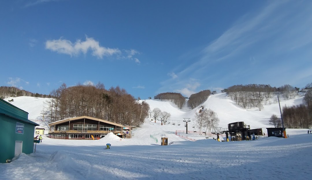 Image showcasing the stunning winter landscape at Rewild Ninja Snow Highland in Japan. The view depicts a bustling ski resort, captured during winter sports activities, and a scenic chalet nearby.