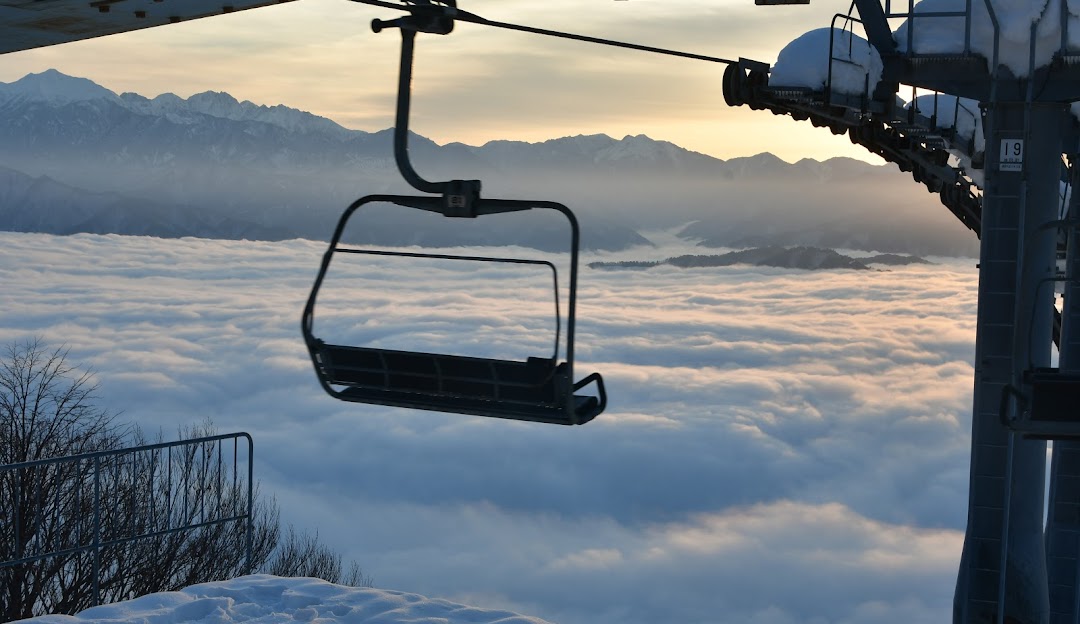View of Star Spur Ryokufu Resort in Japan with a ski lift in prominence, nestled amid alpine terrain in winter. Skiers dot the scene, enjoying the winter sports offerings of the resort.