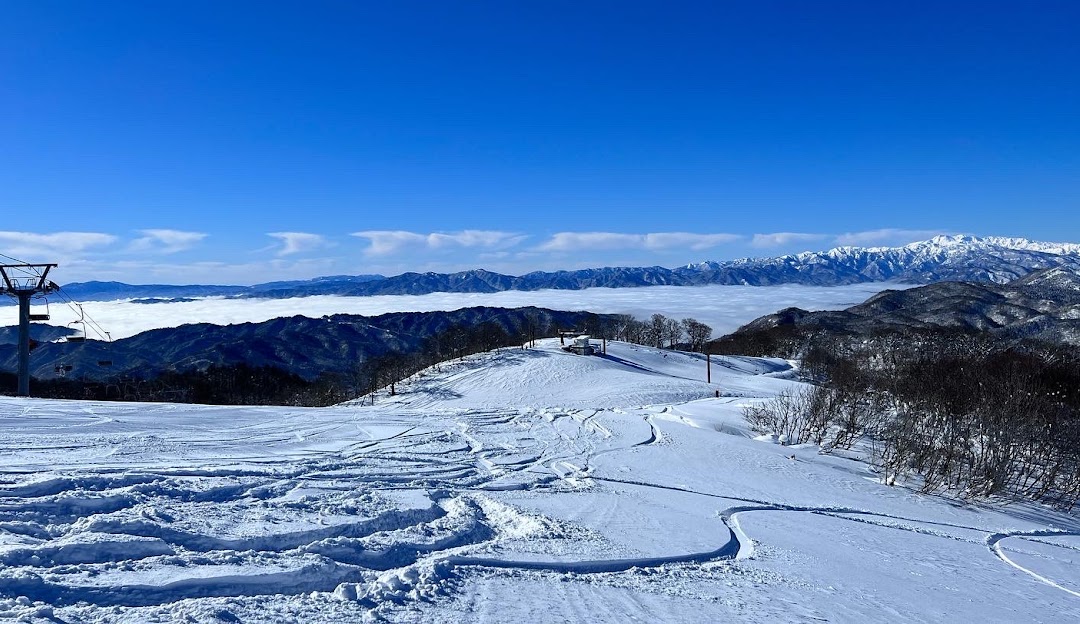 Winter scene at Star Spur Ryokufu Resort in Hida Nagareha, Japan, featuring a stunning snow-swept landscape, bustling with winter sports activities near a cozy chalet.