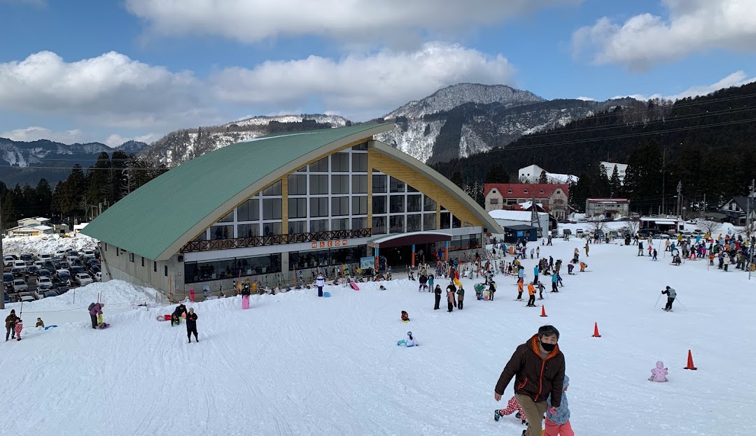 A bustling ski resort in Hida, Japan. Winter sports enthusiasts take advantage of the snow-covered slopes while ski lifts carry others to the top. A charming chalet overlooks the scene.
