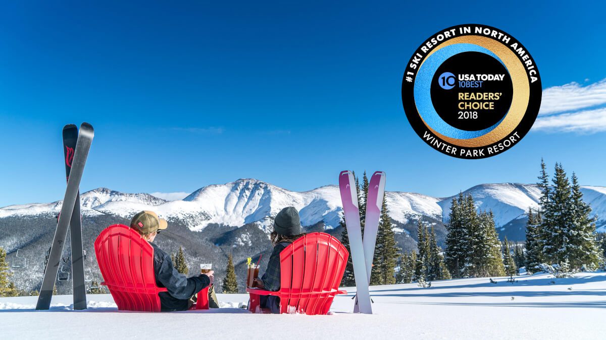 Winter Park Resort in USA - two people sitting in red chairs on a snow covered mountain.