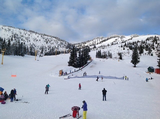 Winter sports enthusiasts enjoy a day on Sasquatch Mountain in Hemlock Valley, British Columbia, Canada, with a ski resort, ski lift, and skier visible in the scene.
