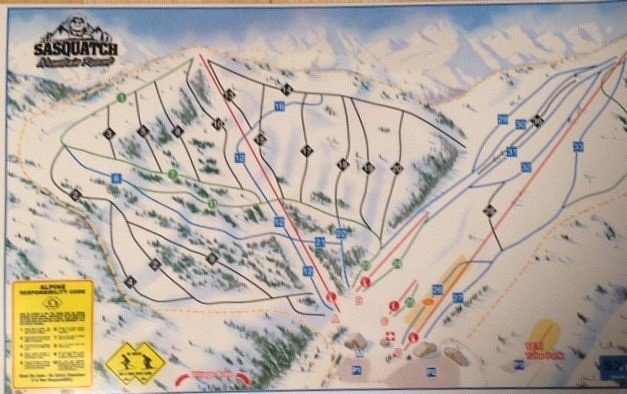 Ski resort on Sasquatch Mountain in Hemlock Valley showing a winter sports scene with scattered chalets, a functioning ski lift, and a lone skier descending the snow-covered slope.