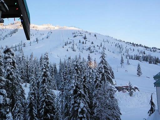 A winter scene at Sasquatch Mountain ski resort in Agassiz British Columbia showcasing a ski lift transporting skiers uphill a cozy challet nearby and visitors partaking in various winter sports.